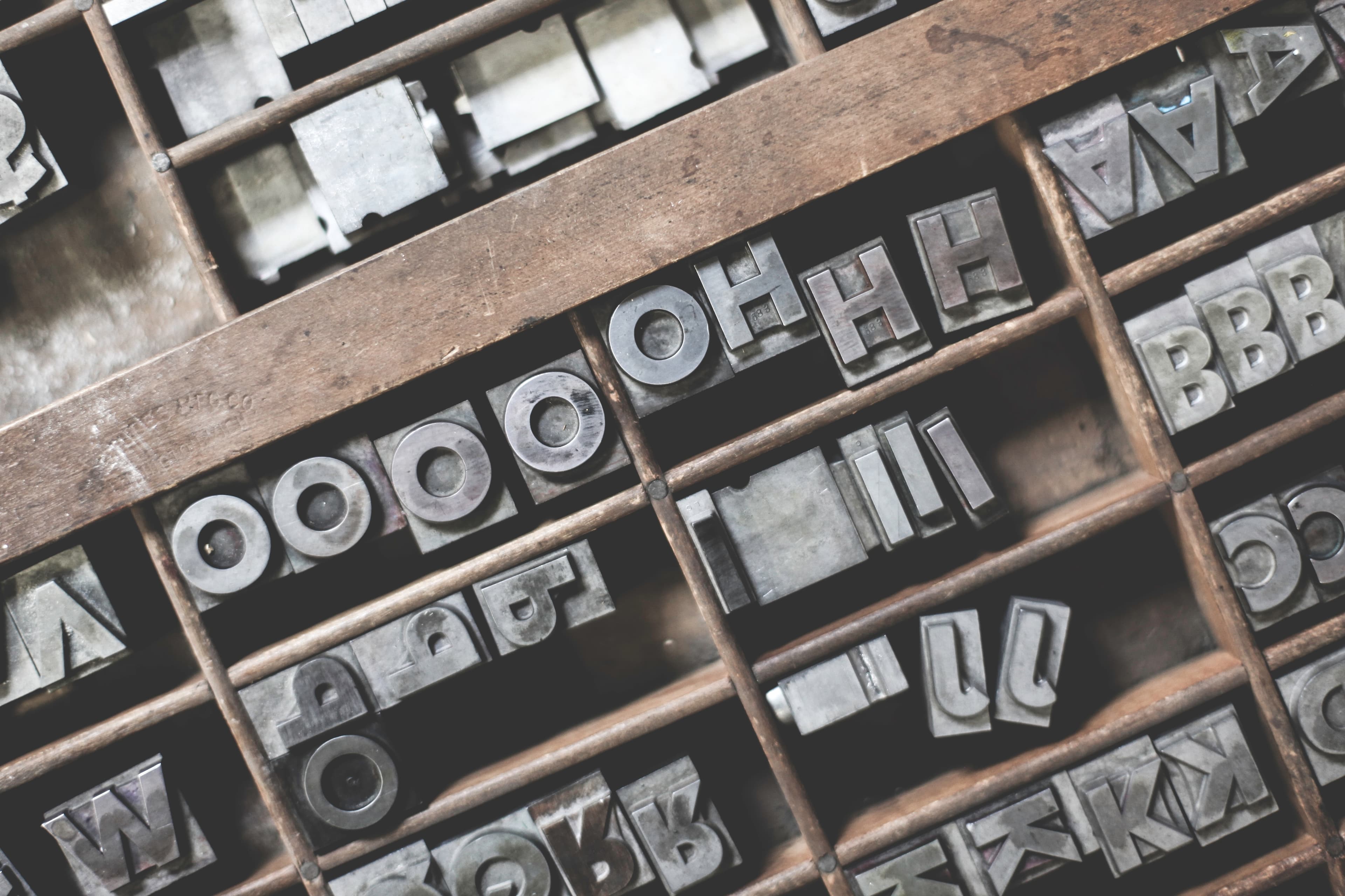 A wooden box with metal type for a printing press inside it.
