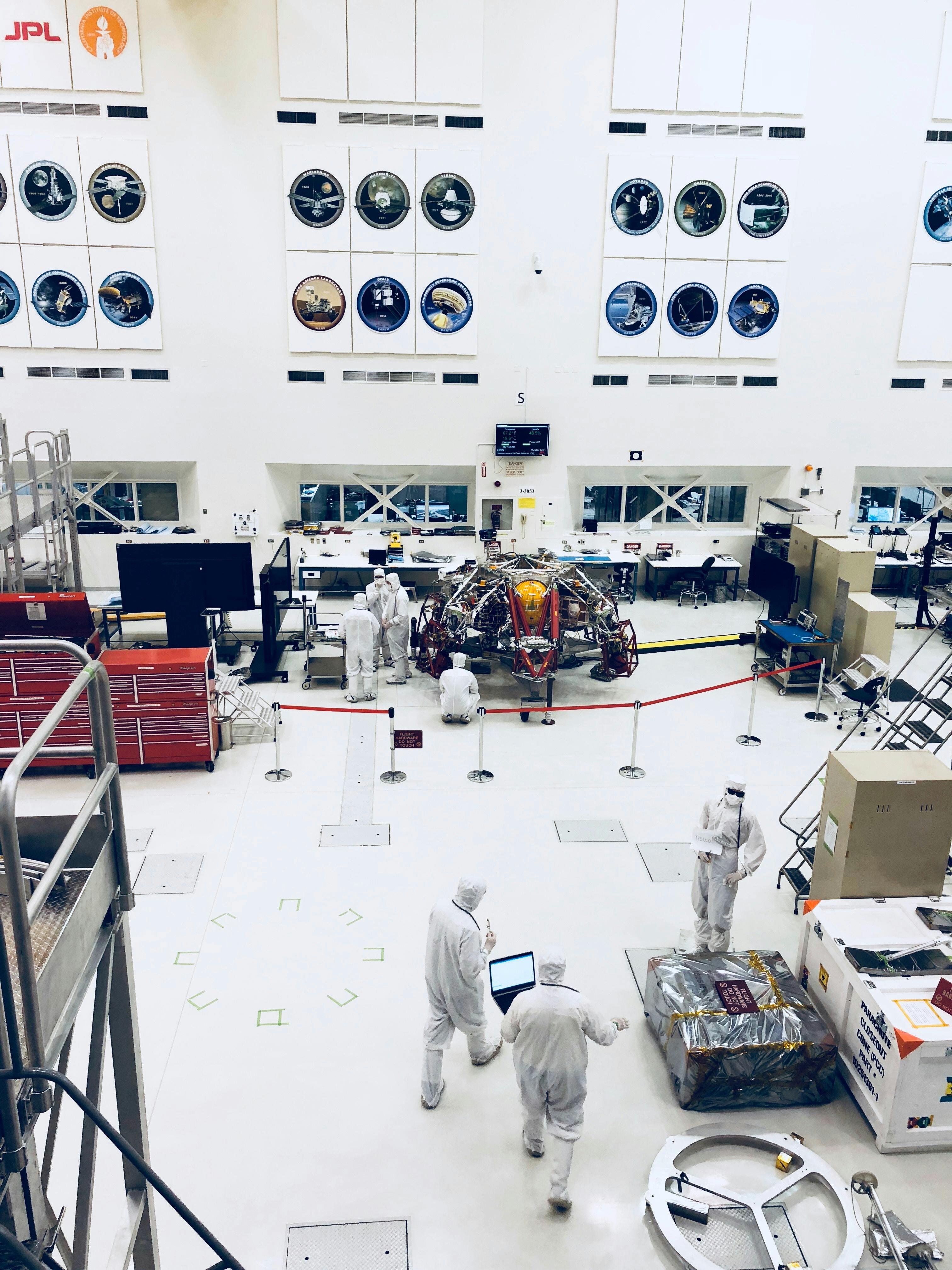 NASA engineers in white clean room suits working on a Mars rover.