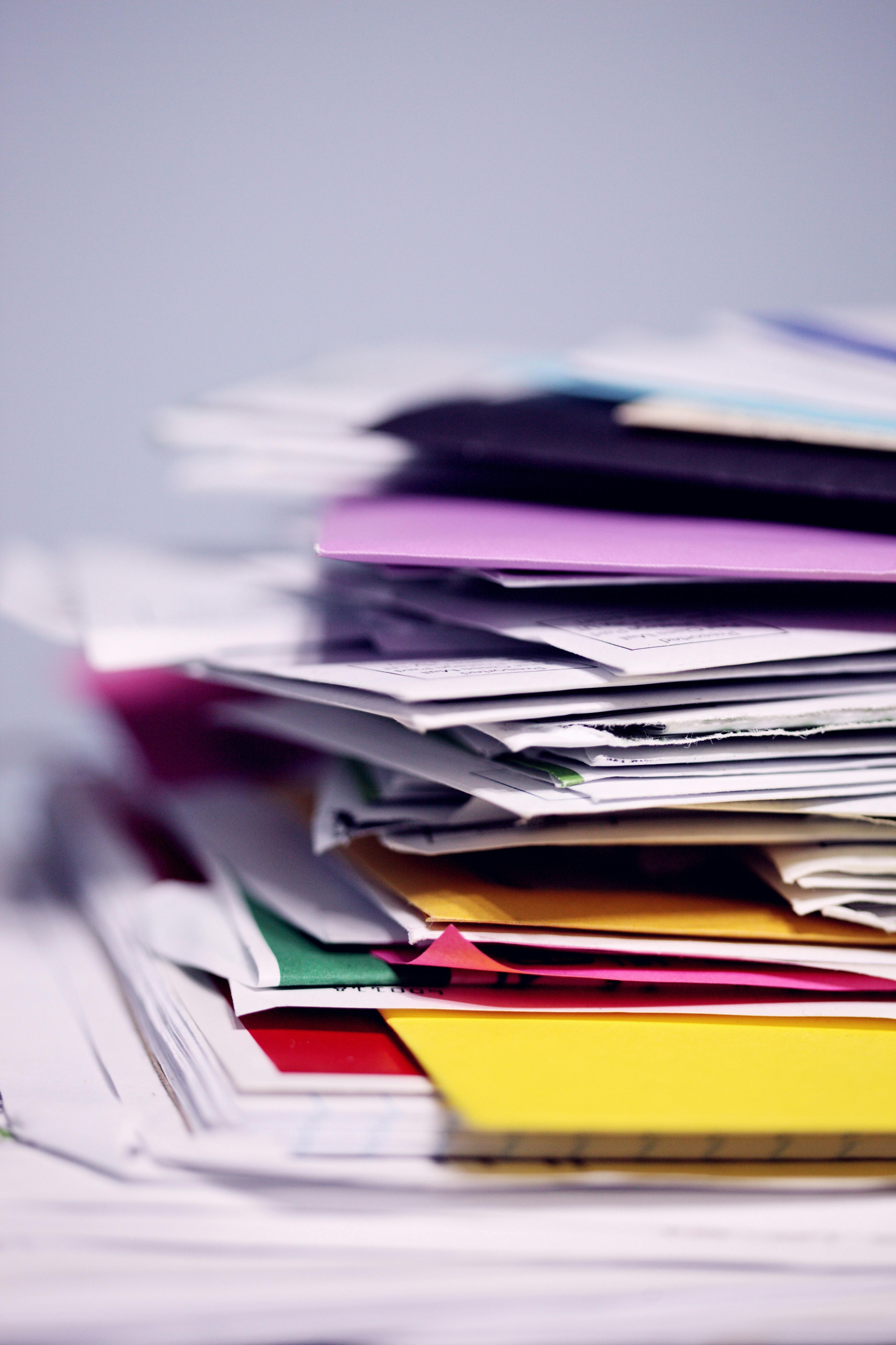 a pile of papers with colorful file folders intermingled.